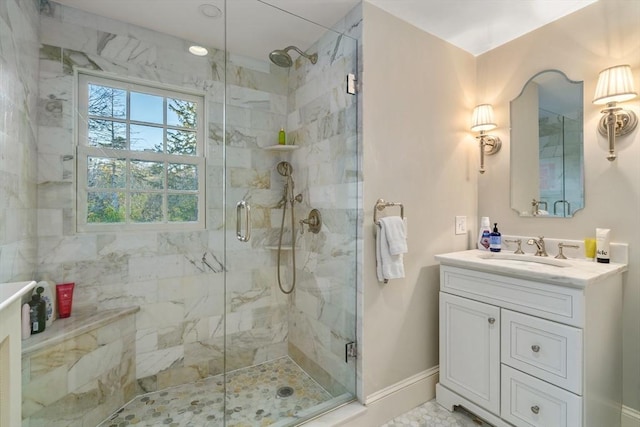 bathroom with a marble finish shower, baseboards, and vanity