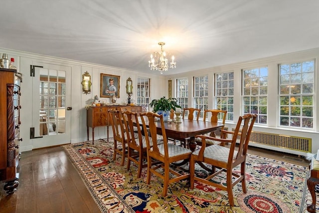 dining space with baseboards, a chandelier, crown molding, radiator, and wood-type flooring