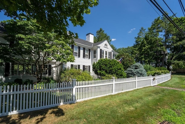 view of front of house with a fenced front yard, a front lawn, and a chimney