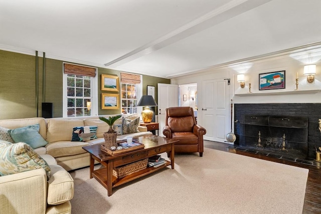 living area featuring a fireplace with flush hearth, wood finished floors, and ornamental molding