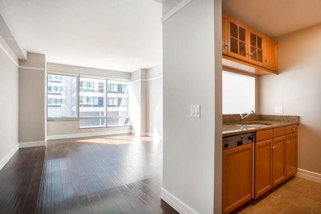 kitchen with glass insert cabinets, baseboards, brown cabinetry, and a sink