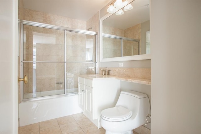 bathroom with toilet, combined bath / shower with glass door, tile patterned flooring, and vanity