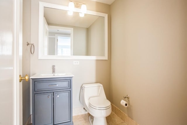 half bathroom featuring vanity, tile patterned flooring, baseboards, and toilet