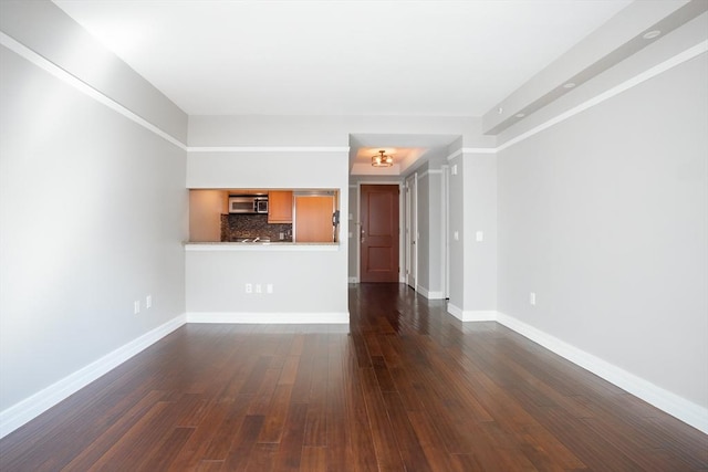 unfurnished living room featuring baseboards and dark wood-style flooring
