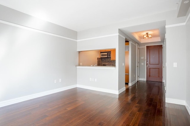 unfurnished living room featuring baseboards and dark wood-style floors