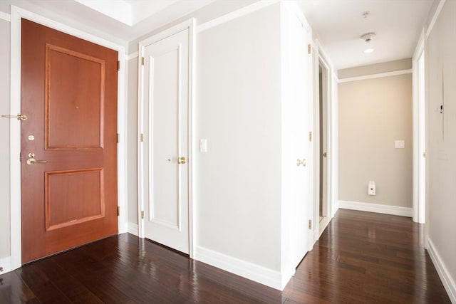 corridor featuring dark wood-style flooring and baseboards
