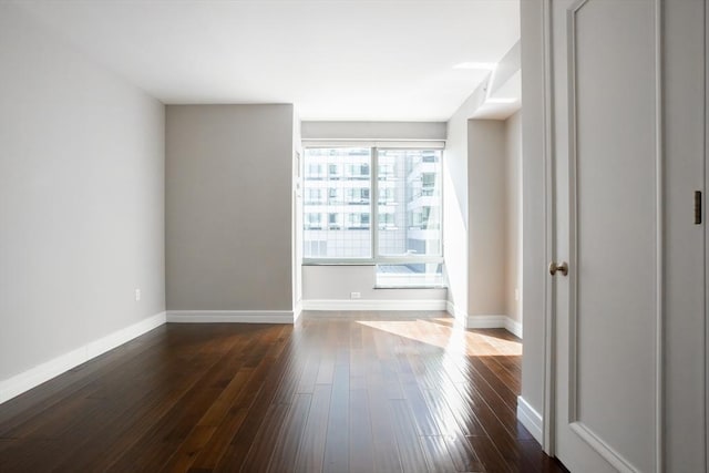 empty room featuring baseboards and dark wood-style flooring