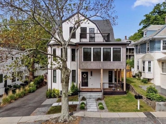 39 Paul St, Watertown, MA 02472 - view of front of property with a balcony, a porch, a gambrel roof, and a front lawn