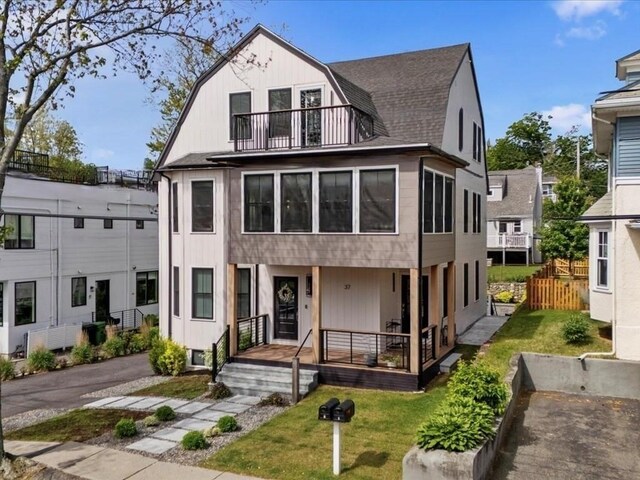 39 Paul St, Watertown, MA 02472 - view of front of home featuring a gambrel roof, a balcony, a porch, a front yard, and roof with shingles