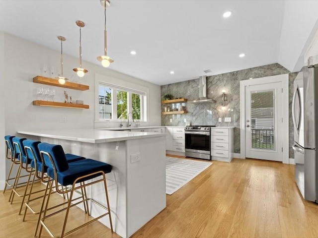 39 Paul St, Watertown, MA 02472 - kitchen featuring stainless steel appliances, open shelves, wall chimney exhaust hood, tasteful backsplash, and a peninsula