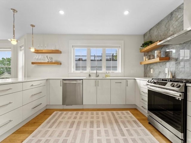 39 Paul St, Watertown, MA 02472 - kitchen with appliances with stainless steel finishes, open shelves, a sink, wall chimney range hood, and tasteful backsplash
