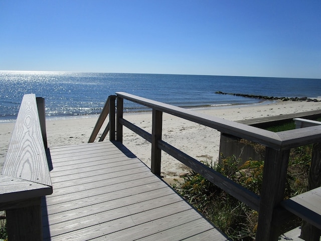 view of dock with a water view and a beach view