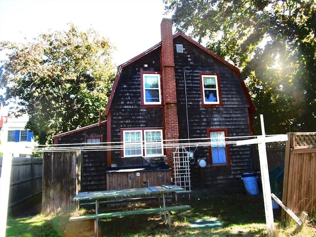 14 Park Pl, Harwich, MA 02646 - back of house featuring fence, a jacuzzi, a chimney, and a gambrel roof