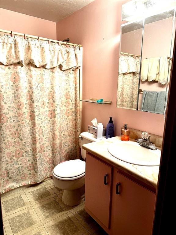 bathroom featuring vanity, a textured ceiling, and toilet