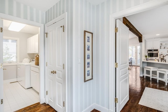 hall featuring dark wood-type flooring, a wealth of natural light, beam ceiling, and wallpapered walls