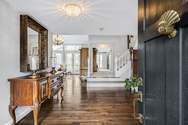 entrance foyer with an inviting chandelier, baseboards, stairway, and wood finished floors