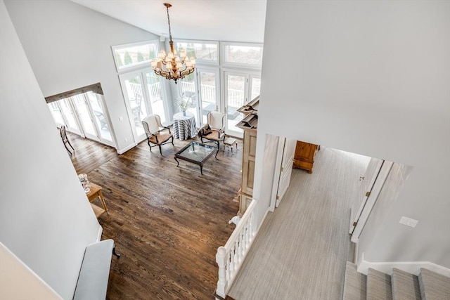 interior space with baseboards, a chandelier, wood finished floors, stairs, and high vaulted ceiling