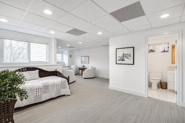 carpeted bedroom featuring ensuite bath, baseboards, a drop ceiling, and recessed lighting