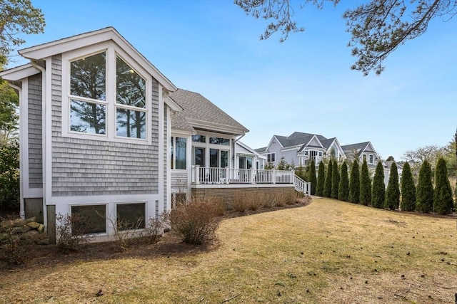 rear view of property with a shingled roof and a lawn