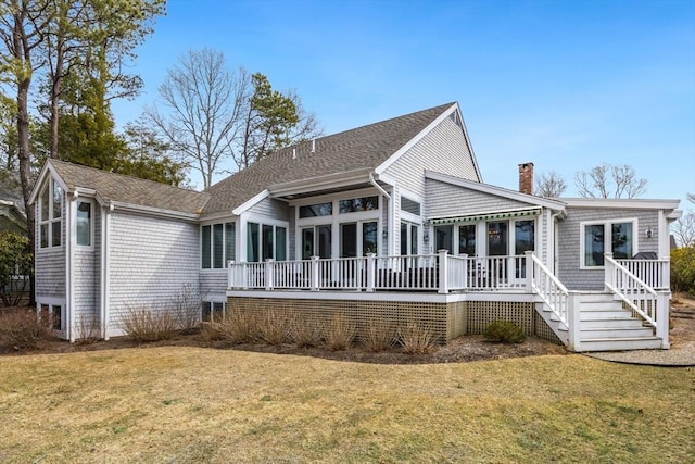 rear view of property featuring a shingled roof, a chimney, and a yard