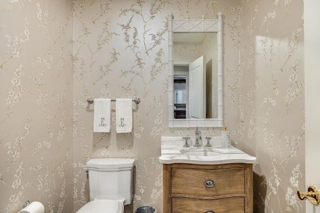 half bathroom with vanity and wallpapered walls