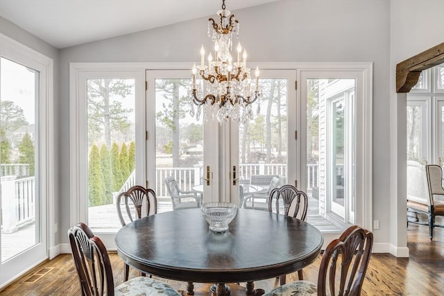 dining room with a notable chandelier, lofted ceiling, visible vents, wood finished floors, and baseboards