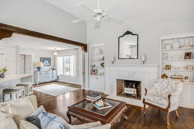 living room with built in shelves, a high end fireplace, vaulted ceiling, wood finished floors, and baseboards