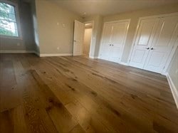 unfurnished bedroom with wood-type flooring and two closets