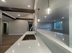 kitchen with beam ceiling, decorative light fixtures, sink, and hardwood / wood-style floors