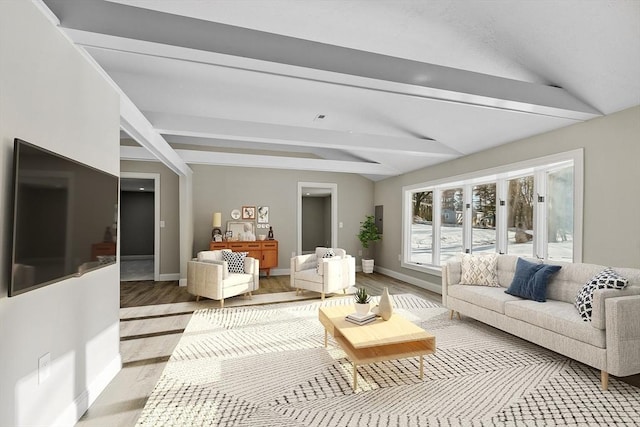 living area featuring baseboards, lofted ceiling with beams, and light wood-style floors