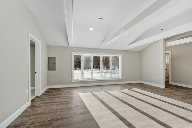 empty room with vaulted ceiling with beams, wood finished floors, visible vents, and baseboards