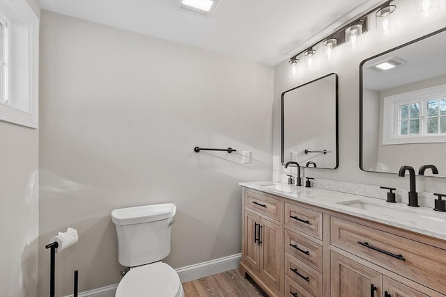 bathroom featuring toilet, wood finished floors, baseboards, and a sink