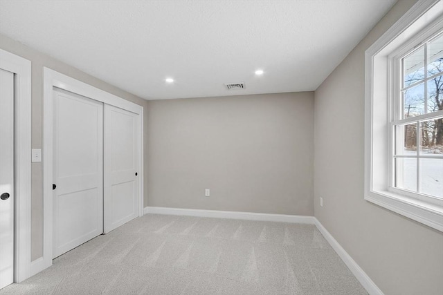 unfurnished bedroom featuring visible vents, baseboards, recessed lighting, a closet, and light carpet