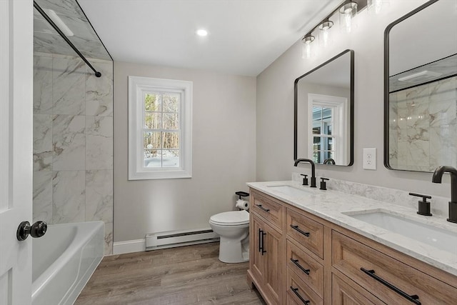 bathroom with a sink, baseboard heating, wood finished floors, and toilet