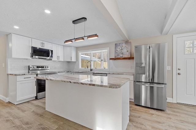 kitchen featuring light wood-type flooring, plenty of natural light, a center island, stainless steel appliances, and light stone countertops