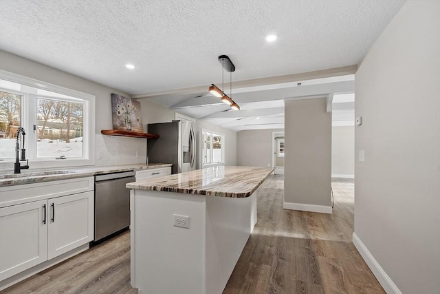 kitchen with a sink, stainless steel appliances, light wood-type flooring, and a center island