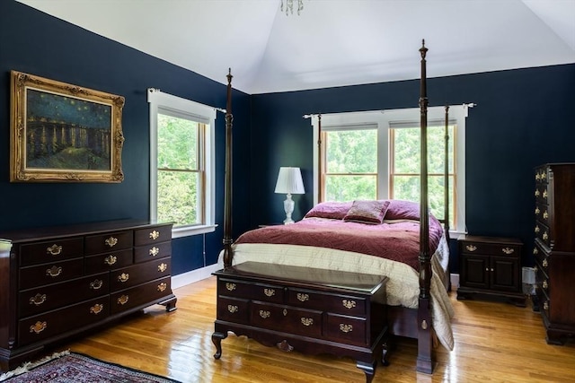 bedroom featuring vaulted ceiling, light hardwood / wood-style flooring, and multiple windows