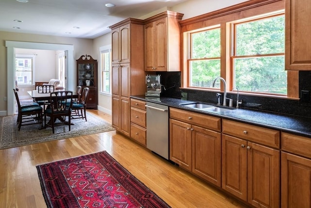 kitchen featuring tasteful backsplash, stainless steel dishwasher, sink, light hardwood / wood-style flooring, and dark stone countertops