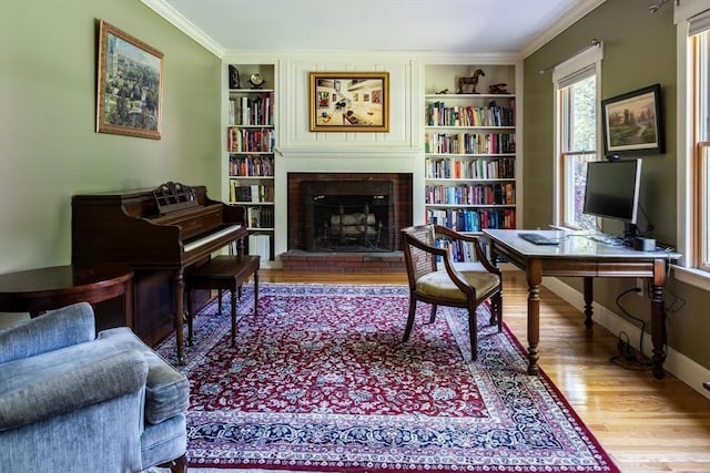 sitting room with crown molding, wood-type flooring, built in features, and a fireplace