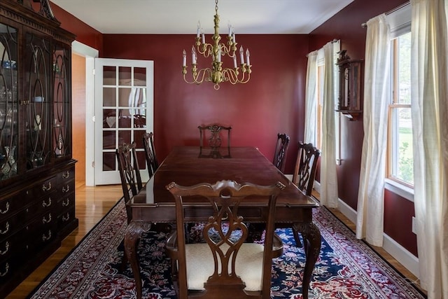 dining area featuring hardwood / wood-style flooring, a healthy amount of sunlight, and an inviting chandelier