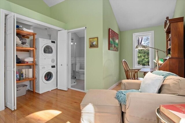 interior space featuring baseboards, light wood finished floors, stacked washer and dryer, and lofted ceiling