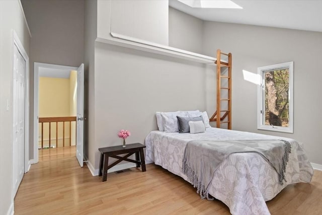bedroom featuring baseboards, light wood finished floors, and a skylight
