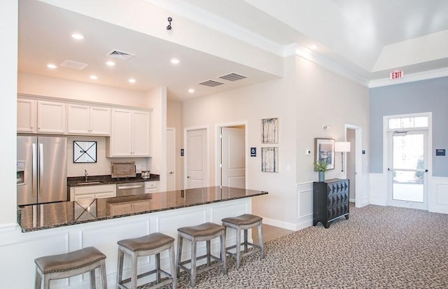 320 Martins Lndg Unit 307, North Reading, MA 01864 - kitchen featuring appliances with stainless steel finishes, a sink, a breakfast bar, white cabinets, and dark stone counters
