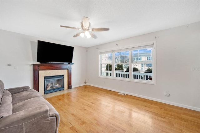 living room featuring hardwood / wood-style flooring, ceiling fan, and a fireplace