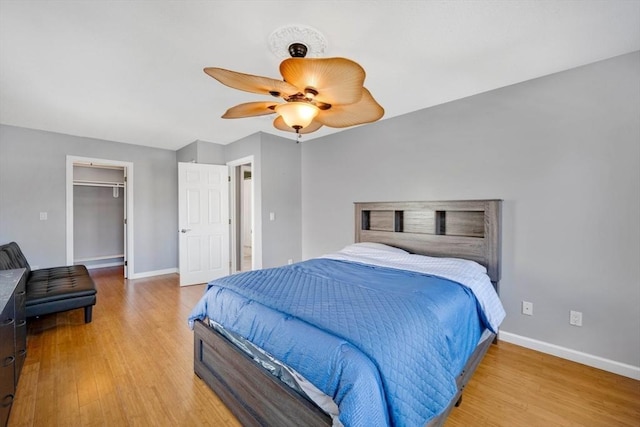 bedroom with a closet, a spacious closet, ceiling fan, and light hardwood / wood-style flooring