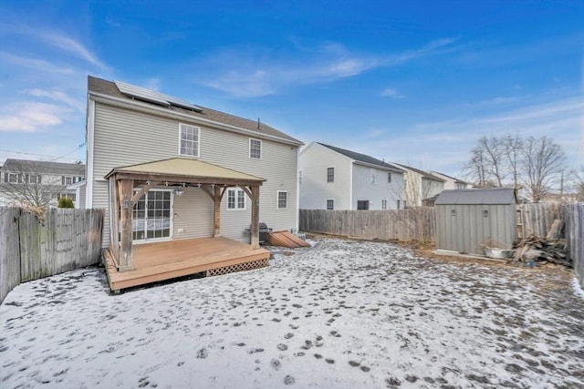 snow covered house featuring a gazebo, a deck, and a storage shed