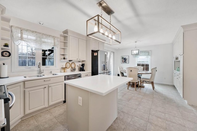 kitchen featuring sink, white cabinetry, stainless steel appliances, a kitchen island, and decorative light fixtures