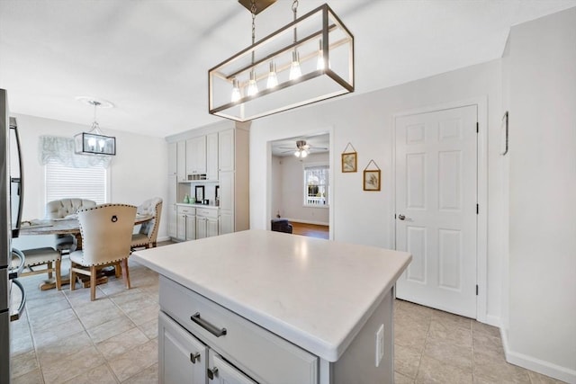 kitchen featuring stainless steel fridge, ceiling fan, white cabinetry, hanging light fixtures, and a kitchen island