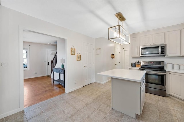 kitchen featuring light tile patterned flooring, a kitchen island, appliances with stainless steel finishes, white cabinets, and hanging light fixtures