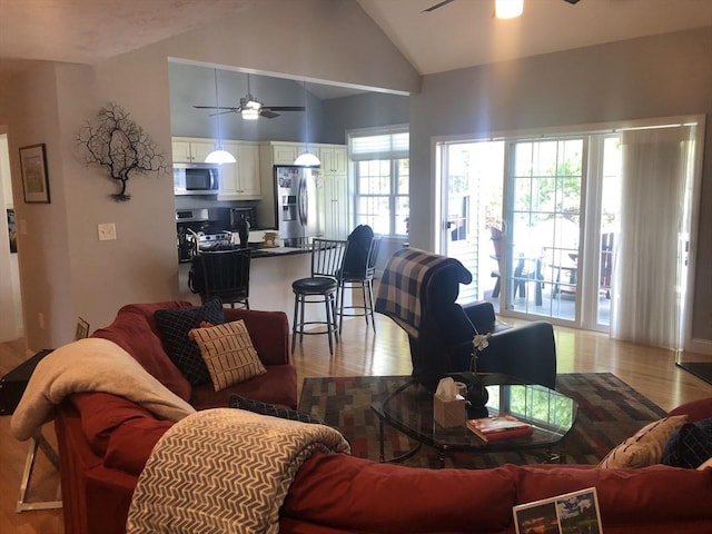 living room with a ceiling fan, high vaulted ceiling, and light wood-type flooring
